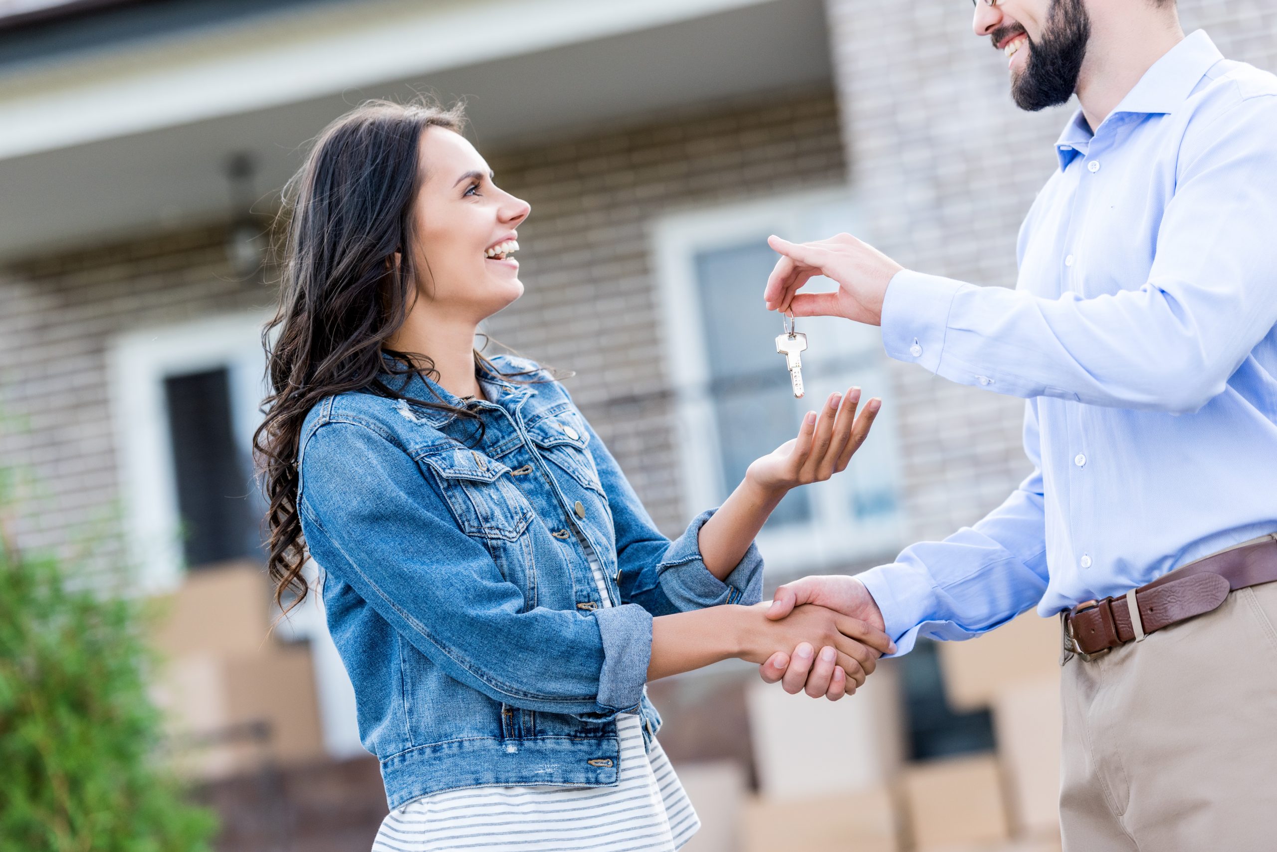 Realtor handing keys to a new house over to a smiling woman