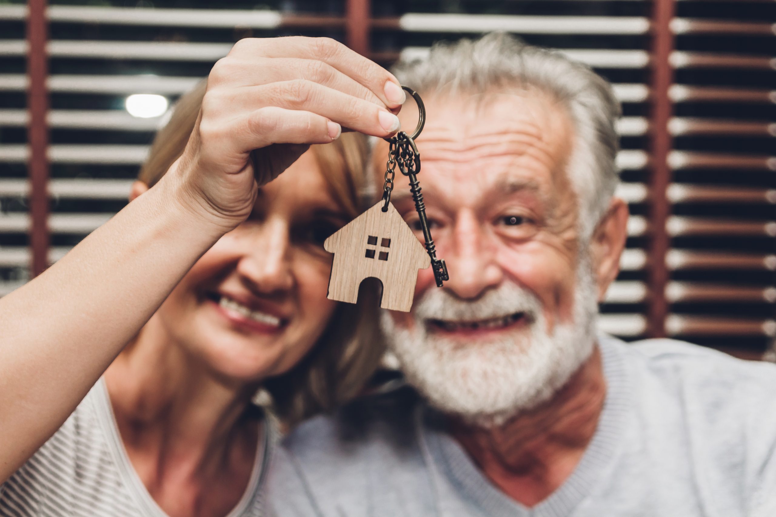An older couple holding up keys to a new home